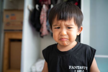 Little asian boy crying bitterly in room of house facial face moodの写真素材