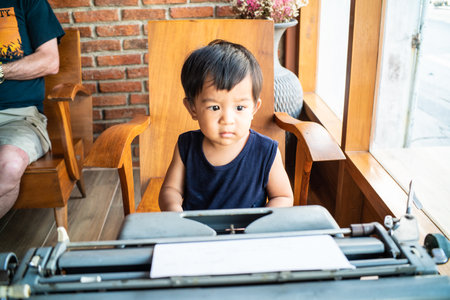 Little boy with the old typewriter in wooden cafe on table learnning kidの写真素材