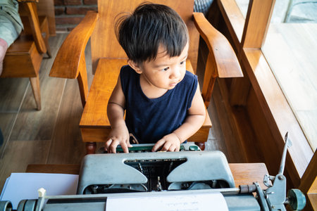 Little boy with the old typewriter in wooden cafe on table learnning kidの写真素材