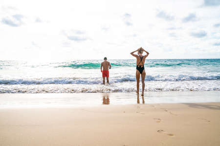 Couple walking on sea beach into the sea summer beachの写真素材