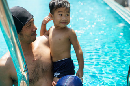 Little boy swimming with father in swimming pool of village recreation activityの写真素材