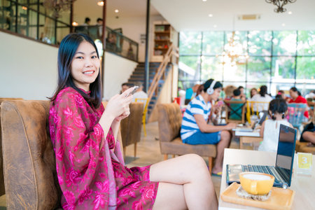 Beautiful asian women texting message on smartphone sitting in coffee shop Business communication conceptの写真素材