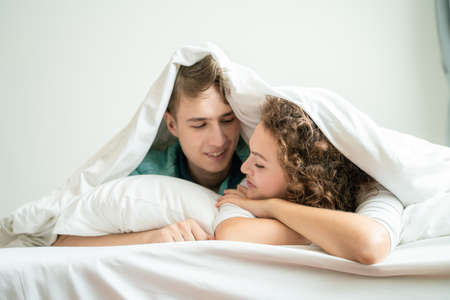 Young happy caucasian couple morning wake up lying together in bed happy peopleの写真素材