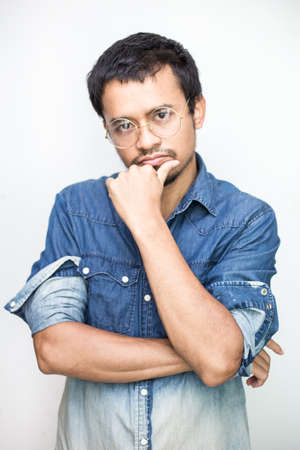 Portrait of handsome beard asian young thoughtful man isolated over white backgroundの写真素材