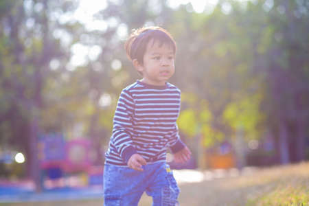 Aorable little boy running on green grass in morning park sun rise exercise of childの写真素材