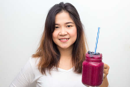 Woman drinking healthy fruit vegetable berry juice smoothie made of super foods fruits and berries on white backgroundの写真素材