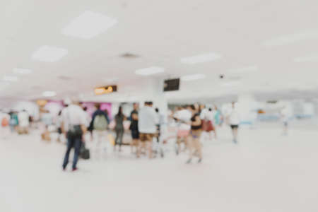 Blurred many anonymous tourist people  walking in a modern airport hall rush hourの写真素材