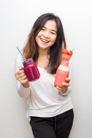 Beautiful healthy glasses women drinking strawberry and blueberry smotthie yogurt on white backgroundの写真素材