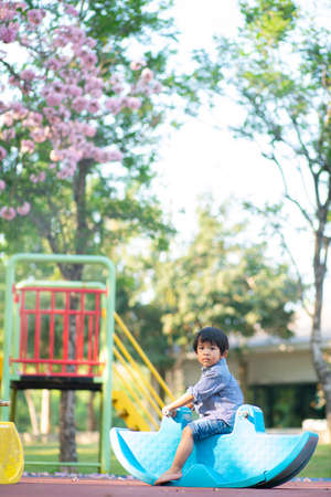 Funny cute happy baby playing rocking horse on the flower tree playground. The emotion of happinessの写真素材