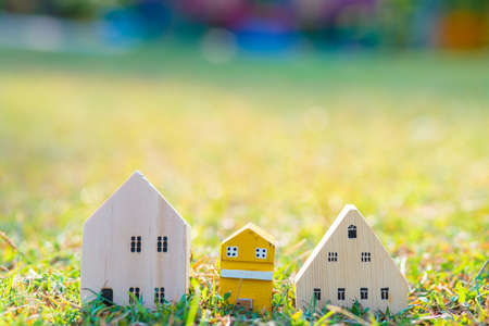 Small model of wooden home over green grass morning sun light, Eco house conceptの写真素材
