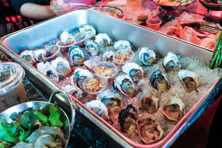 Fresh sea oysters served on metal plate with iceの写真素材