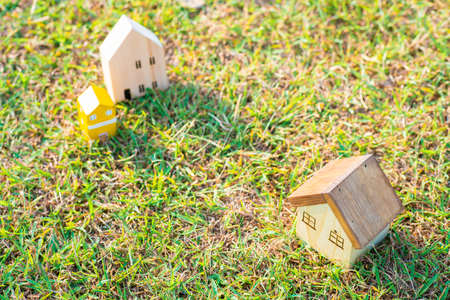 Small model of wooden home over green grass morning sun light, Eco house conceptの写真素材