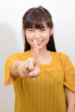 Happy young smiling woman pointing her finger standing isolated over white backgroundの写真素材