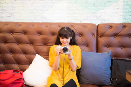 Hipster beautiful asian women take photo with camera while sitting in loft cafe asian womenの写真素材
