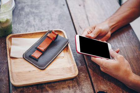 Business man hand use smartphone on wood table with ice green tea hand close up