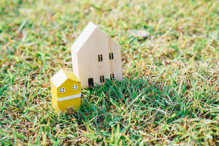 Wooden toy house model on green grass new home business conceptの写真素材