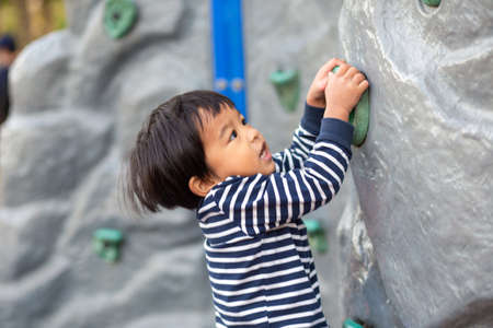 Faunny happy  3 year boy climbing on playground outdoor park recreation in morningの写真素材