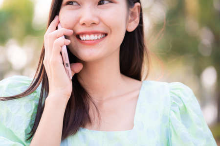 Smiling beautiful women talking smartphone in outdoor city park business casual womenの写真素材