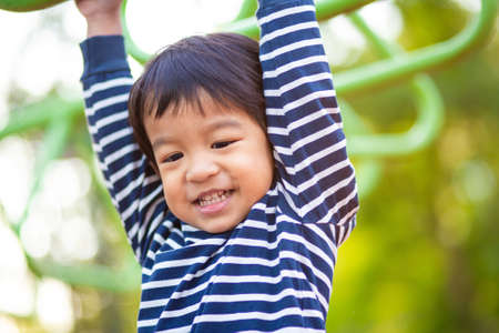 Faunny happy  3 year boy climbing on playground outdoor park recreation in morningの写真素材