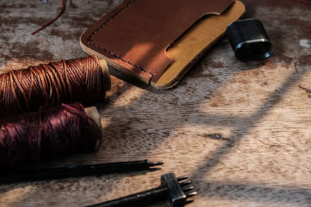 Genuine leather card holder wallet with tool on wood background craftmanship working