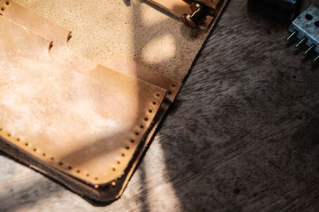 Genuine leather card holder wallet with tool on wood background craftmanship working