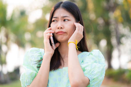 Portrait of asian beautiful women talking on smartphone in outdoor park social distanctingの写真素材