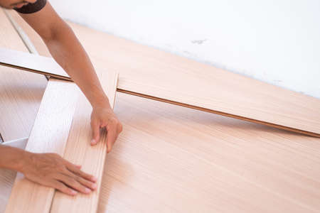 Man setiing laminate brown wood floor in new modern house asset conceptの写真素材