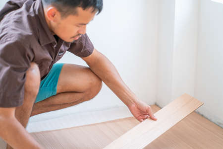 Man setiing laminate brown wood floor in new modern house asset conceptの写真素材