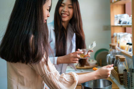 Young female asian women friends cooking in kitchen preparing together meal at homeの写真素材