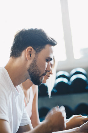 Couple of men women use smartphone talking together after working out in fitness gymの写真素材