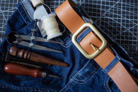 Leather belt brass buckle on jean pant with craftmanship working tool