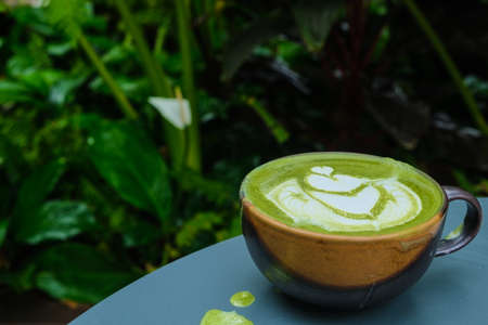 Hot latte art matcha coffee in garden coffee shop drink with nature aroma