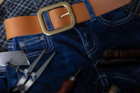 Leather belt brass buckle on jean pant with craftmanship working toolの写真素材