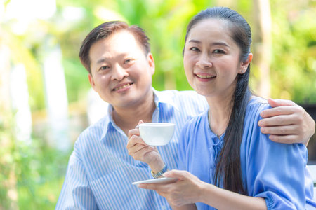 Senior couple drink hot coffee together siting in home garden happy seniorの写真素材
