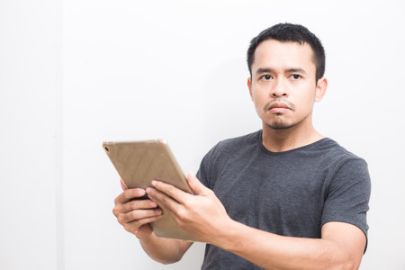Business asian man use ipad tablet computer standing on white backgroundの写真素材
