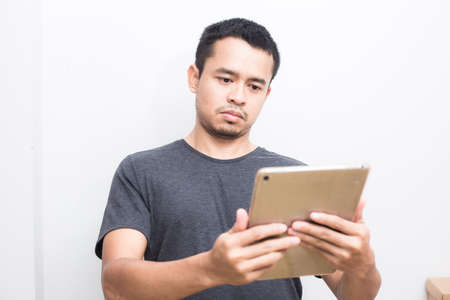 Business asian man use ipad tablet computer standing on white backgroundの写真素材