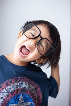 Happy facial face of little boy with big glasses on white background funny emotion