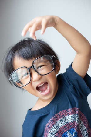 Happy facial face of little boy with big glasses on white background funny emotionの写真素材