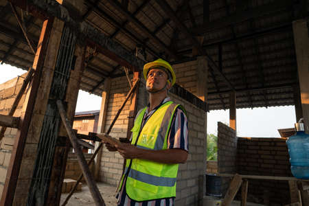Foreman inspecture new house building holding tablet computeer for record data in construction site
