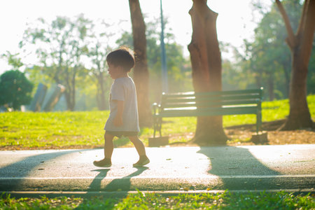 Boy walking on green grass in city park sunset light boy outdoor activityの写真素材
