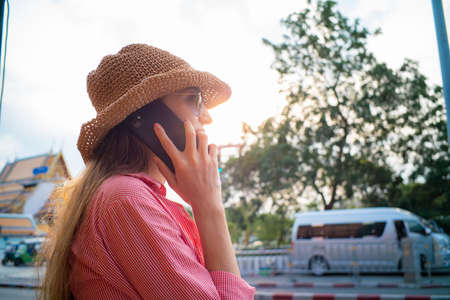 Young beautiful blonde woman on vacation wearing summer hat using smartphone at street of city happy womenの写真素材