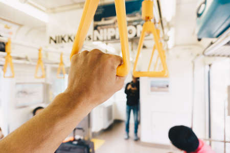 Close-up of a man's hand holding a yellow handle of a train.の写真素材