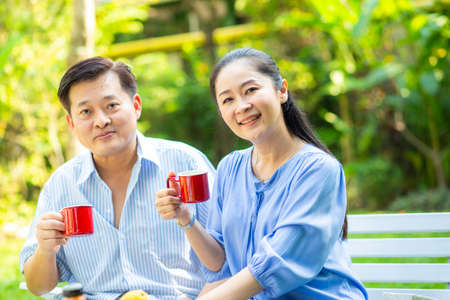 Happy asian senior couple taking with coffee drink in green garden happy morningの写真素材