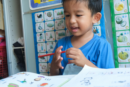 Happy kindergarten boy drawing pencilo color homework in home education conceptの写真素材