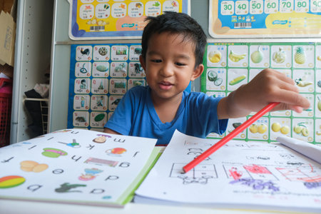 Happy kindergarten boy drawing pencilo color homework in home education conceptの写真素材