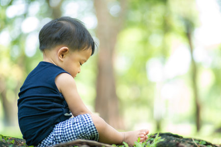 Toddler asian 2 year boy playing on green grass in nature park outdoor activityの写真素材