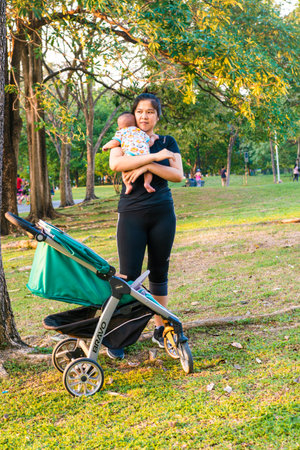 Asian mom hold baby kid boy recreation in city park sunset outdoor activity
