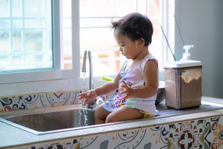 Adorable asian baby girl shower on disk sink enjoying with water happy girlの写真素材