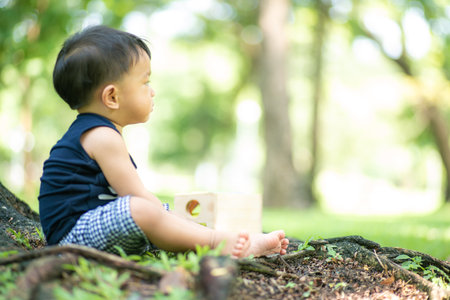 Toddler asian boy playing wooden toy in city green park outdoor activityの写真素材