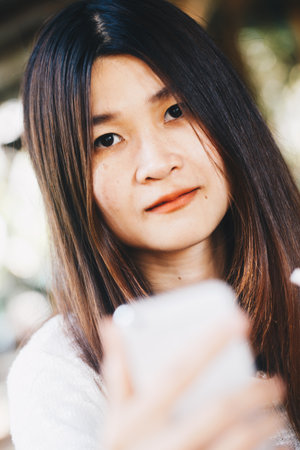 Asian beautiful women talking on smart phone while sitting in cafe, Business women with cellphoneの写真素材